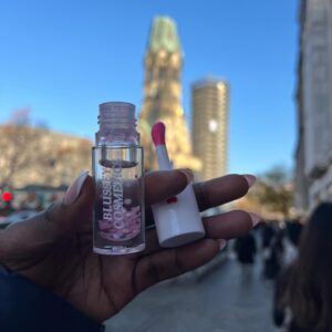 A female hand holding the sweet melody lip gloss in an outdoor setting